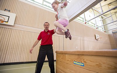 Kind springt in der Turnhalle über einen Kasten